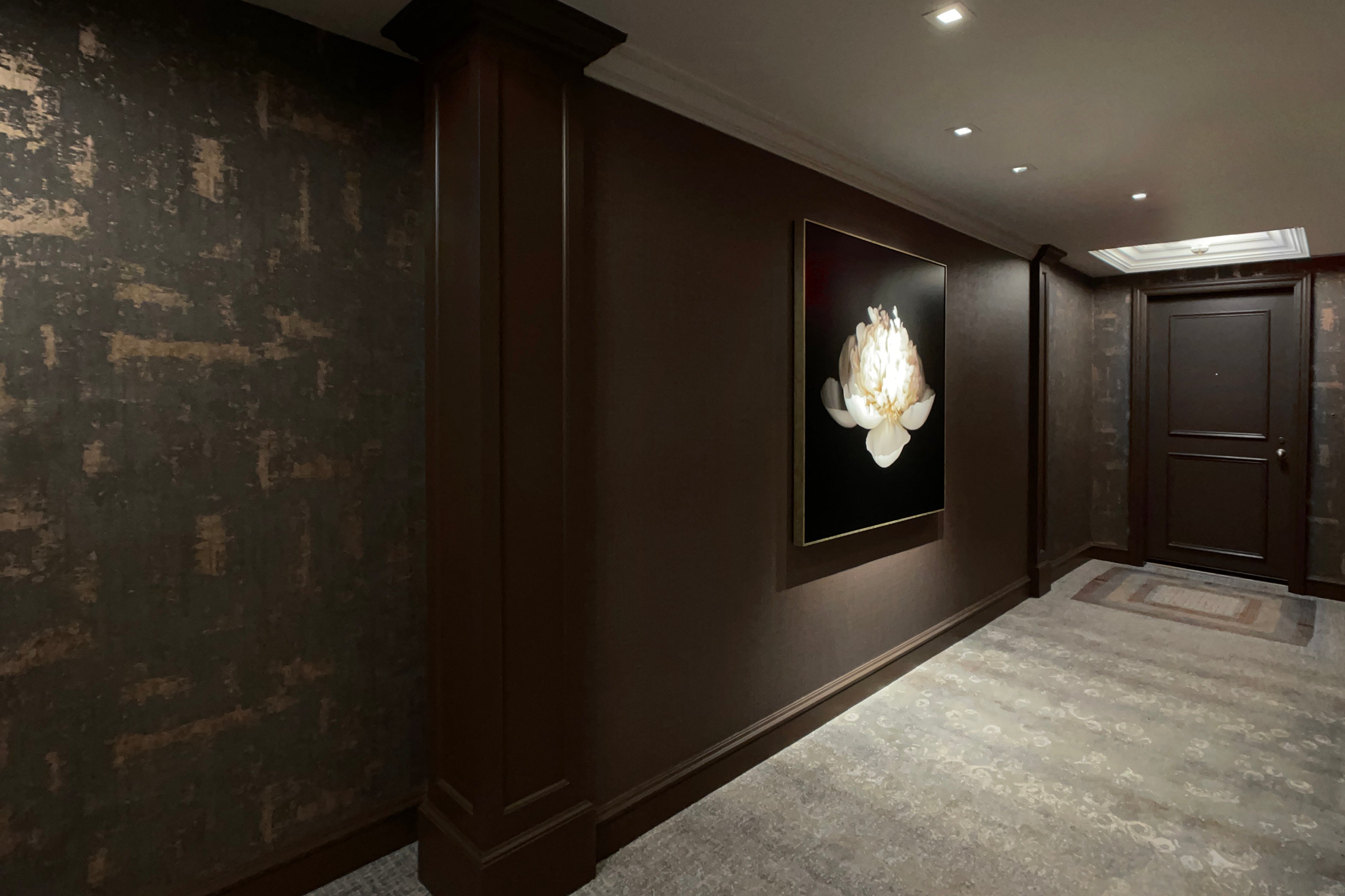 Long view of a framed Doris Mitsch print: a large white peony on a dark background, hanging in the corridor.